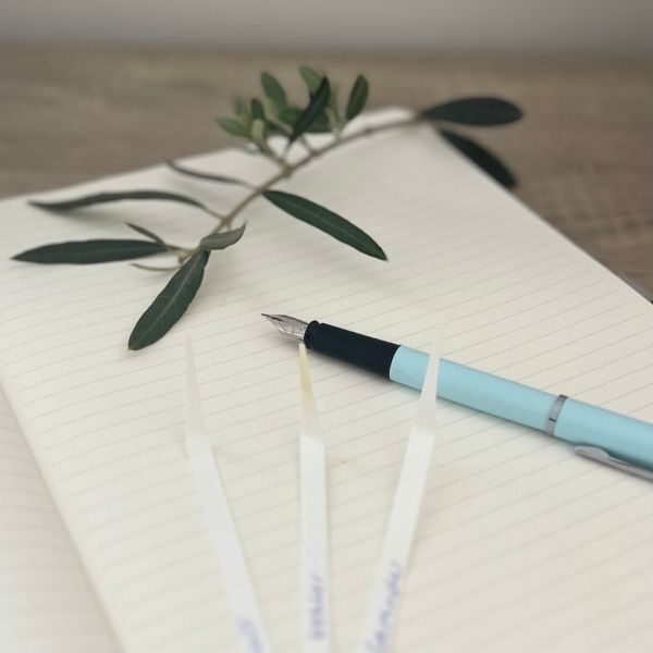 Aroma Studio - sniff papers, blue pen and greenery sitting on an open notepad with lined paper